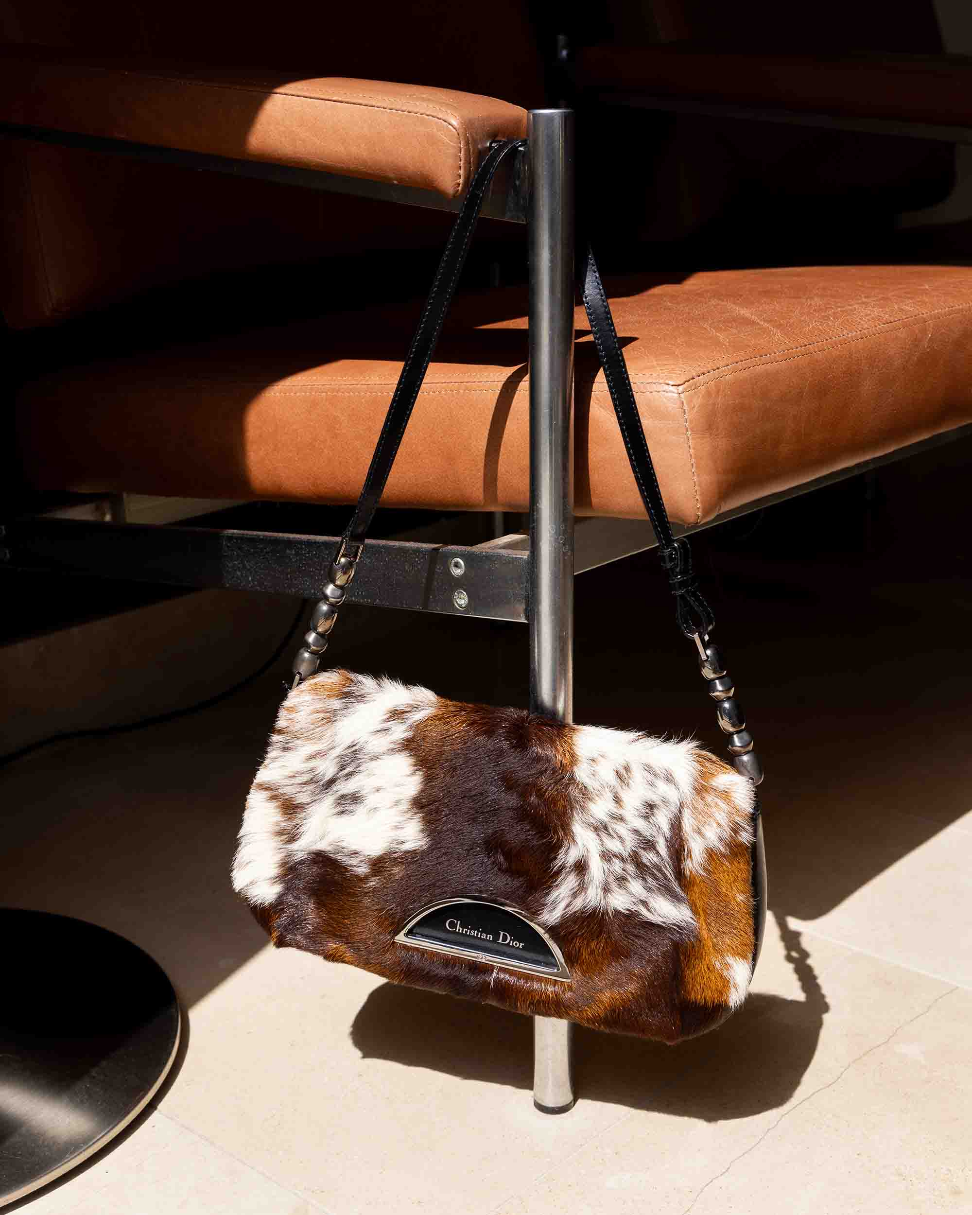 Christian Dior bag draped over leather chair in home